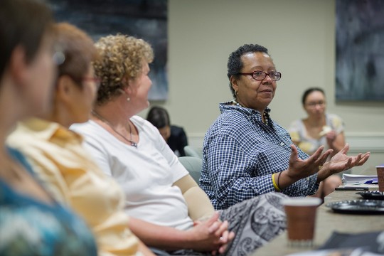 professor speaking while sitting at table with other women.
