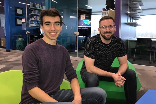 student and staff member sitting in green chairs.