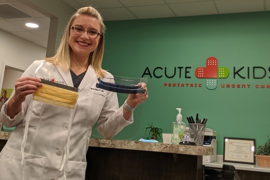 a person in a lab coat holding up face masks and visors