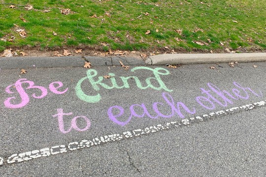 sidewalk chalk art that says Be kind to each other.