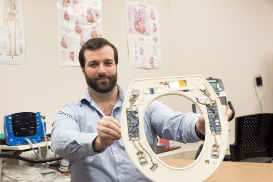 researcher holding toilet seat embedded with sensors.