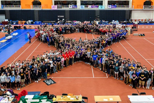 crowd of people standing in the shape of a ribbon.