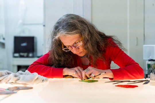 woman working on stained-glass art piece.