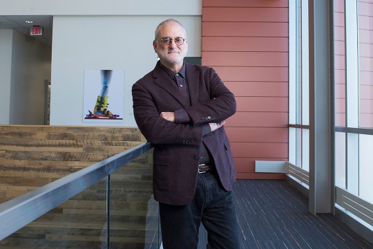 professor standing in hallway with arms crossed.