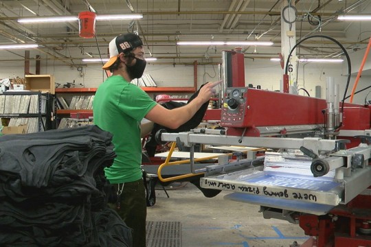 worker setting a machine to screen-print T-shirts.