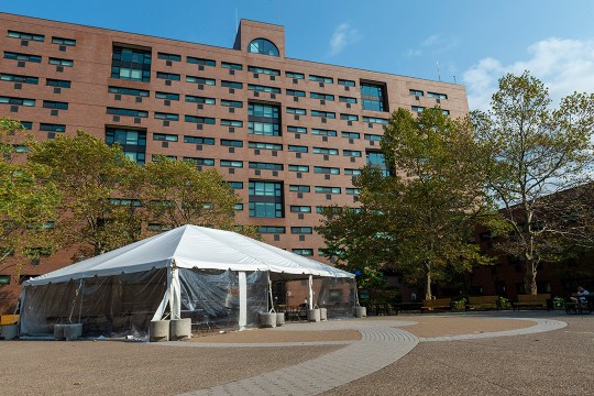 party tent set up outside of brick building.