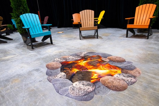 Adirondack chairs spaced out around a life-size photo of a firepit.