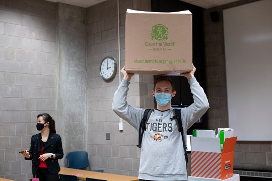student holding cardboard box above his head.