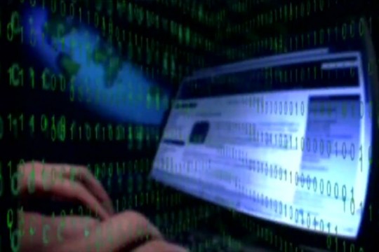 person typing on computer with an overlay of green zeros and ones.