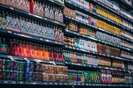 grocery store shelves with cans and bottles of pop and beer.