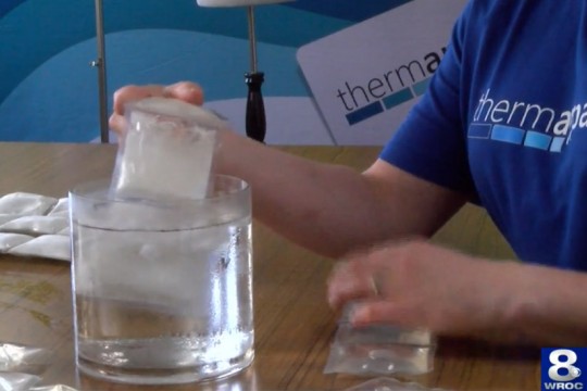 person dipping cooling packs into a container of water.