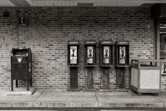 black-and-white bank of payphones outside a convenience store.