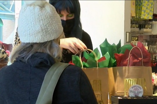 cashier bagging customer's times with green and red tissue paper.