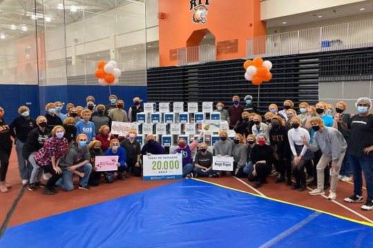 group of people posing for a photo around a pyramid of boxes.