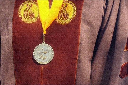 A closeup of a doctoral graduation robe and a medal.
