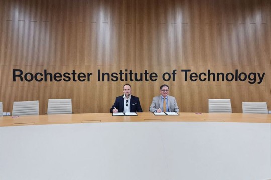 two people sitting next to each other at a large boardroom table.