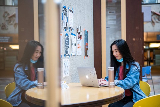 student sitting at a table in the Student Alumni Union working on a laptop.
