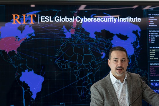 man speaking at podium in front of a screen showing a world map.