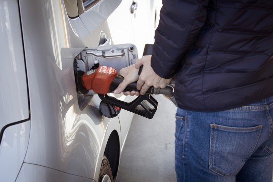 person pumping gas into a vehicle.