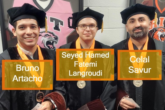 Three Ph.D. graduates wearing regalia.
