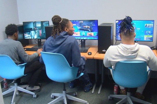 three students sitting at desks with computers.
