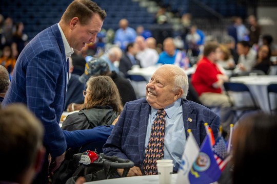 person standing and talking to another person in a wheelchair.