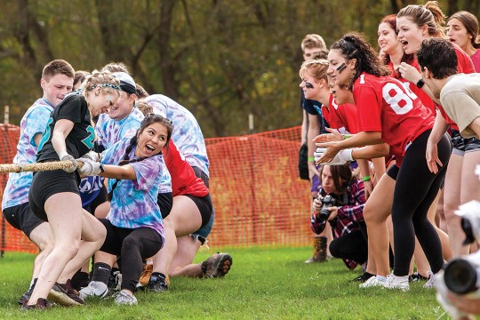 crowd of college students cheering on one side of a tug of war team.