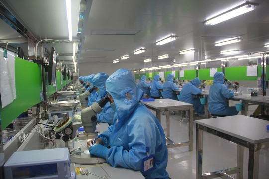 People in blue sanitary suits working in a lab.