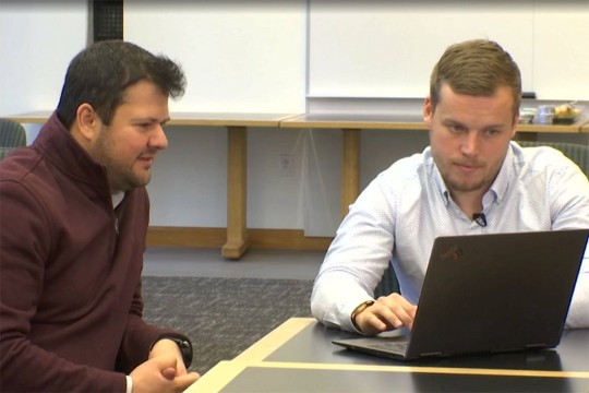 two men looking at a laptop computer.