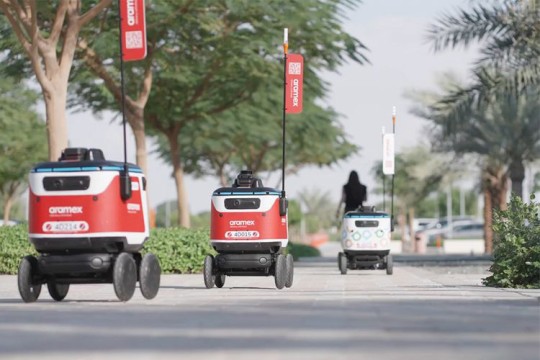 three small robot cars driving down a sidewalk.