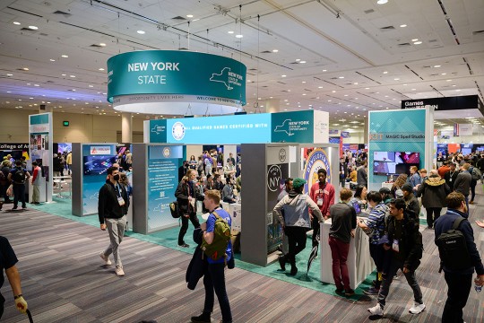 several booths under a New York State sign at the Game Developers Conference.