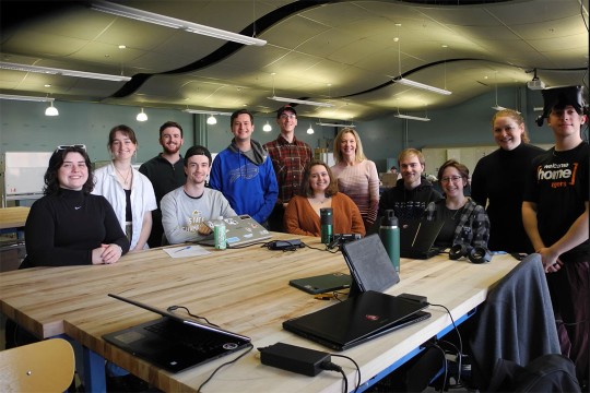 team of college students and professor sitting around a table.