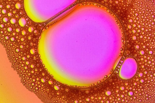 close up of shampoo, showing large and small purple, yellow and orange bubbles.