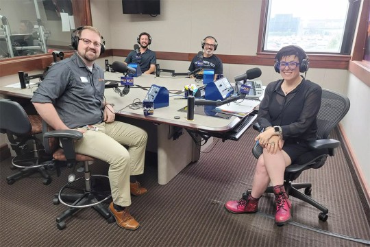 four people sitting around a table in a radio station.