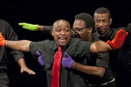 three Black men wearing colorful knit gloves performing in American Sign Language.