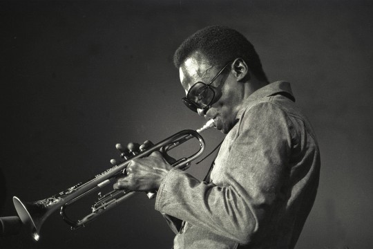  a black and white photo of Miles Davis playing the trumpet in 1969.