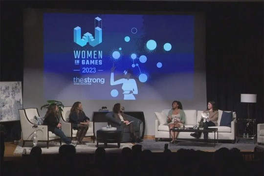 five panelists sitting on couches on a stage with a screen projected behind them that reads, Women in Games 20 23.