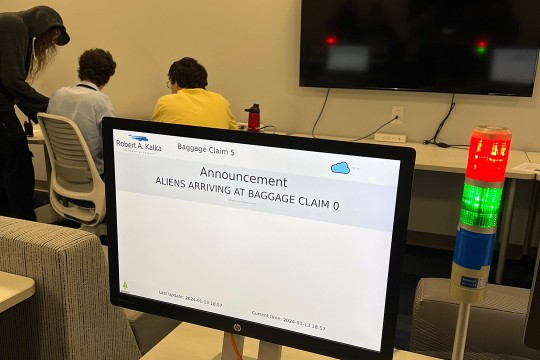a computer screen with the message, announcement, aliens arriving at baggage claim zero.