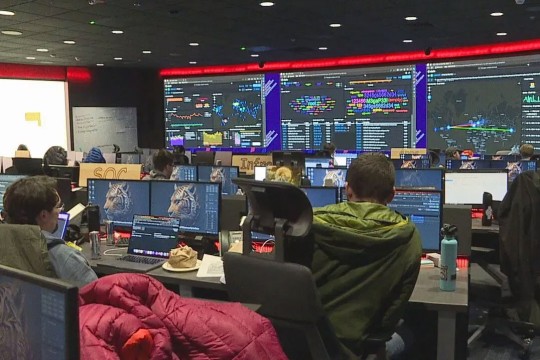 college students in a computer lab with large screens on the wall showing fake attacks on an airport.