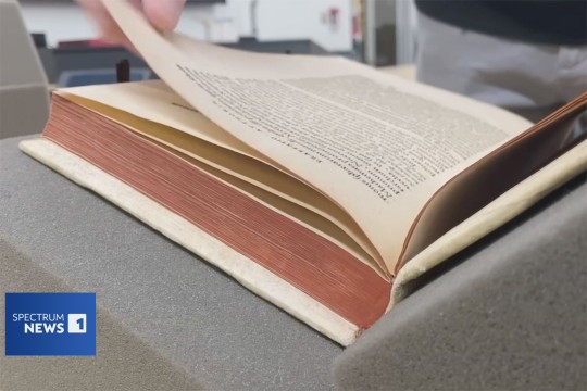 a centuries old text appears on the screen being handled delicately