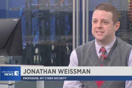 Jonathan Weissman is shown on the screen for Spectrum News with a chyron stating his name and role at RIT in front of him