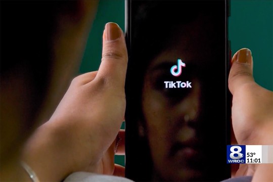 hands hold a phone that is loading the TikTok app.