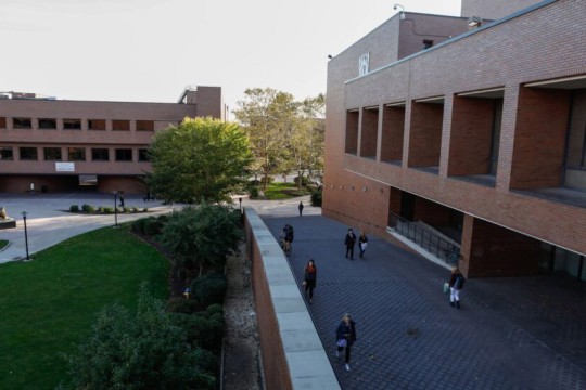 'buildings on the RIT campus are shown with students walking in the pathways between.'