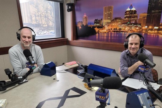 Joel Helfrich is shown seated next to Evan Dawson with headphones on and microphones in front of them.