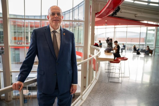 David Munson, Jr., RIT President, stands on a balcony on the second level of the SHED.
