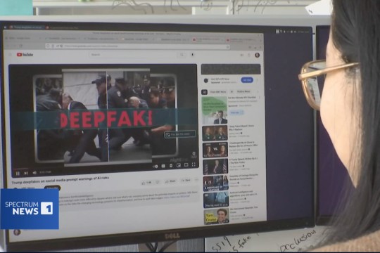 the profile of a woman is shown looking at a computer screen displaying the words deepfake over a photo of Donald Trump.