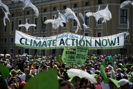 'People outside an ornate building hold a sign that says Climate action now'
