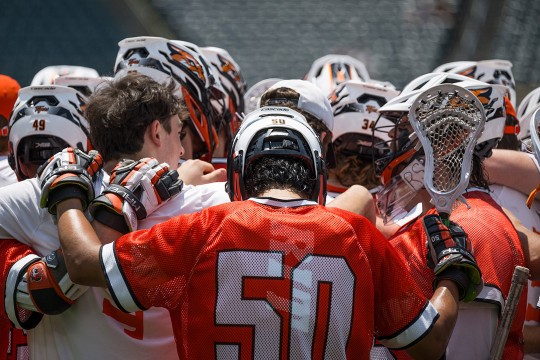 The R I T men's lacrosse team is shown in a huddle.