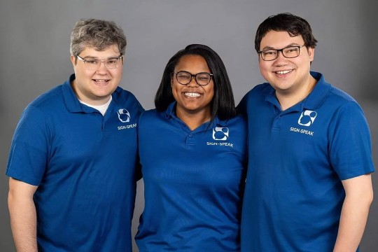 three people in blue polo shirts stand together for a photo.