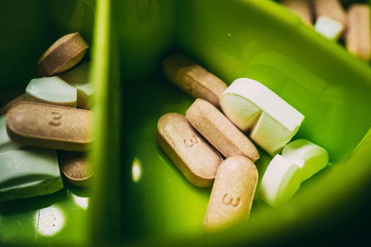an assortment of pills are shown in a green tray.